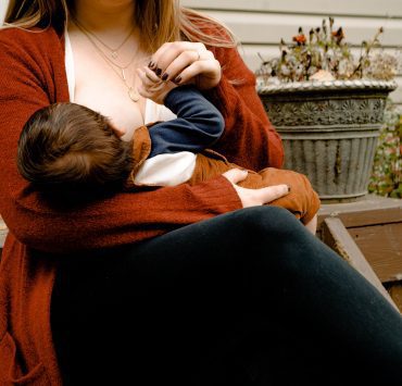 New mom holding baby during feeding, highlighting breastfeeding support and bonding.
