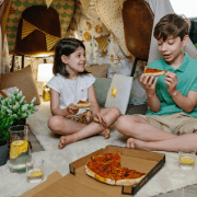 Kids under a fort eating pizza