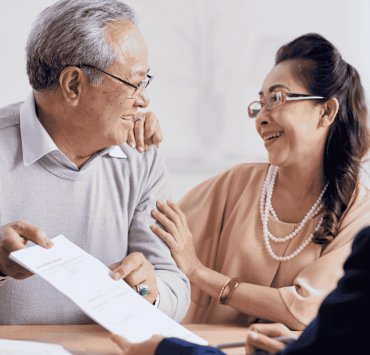 Senior couple reviewing estate planning documents with a lawyer in an office.
