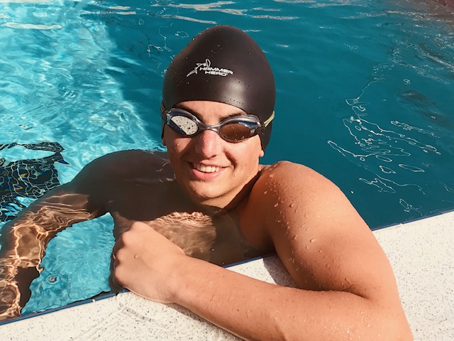 Young swimmer wearing a protective swim cap during summer league practice.