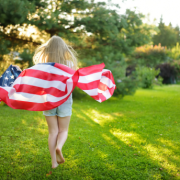 American flag waving outdoors with a little girl against a blue sky